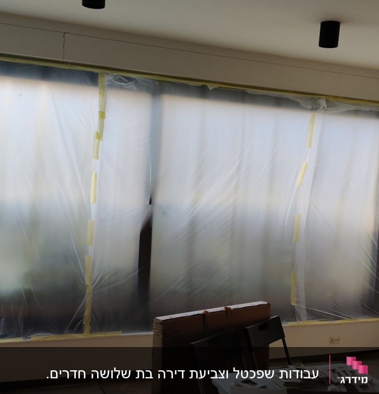 חלון מכוסה בניילון לקראת צביעה